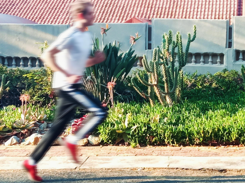 Photograph of Edward Rycroft running on a road with the background in focus while he is blurred.